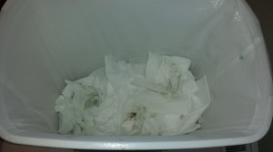 A garbage can full of used tissues.